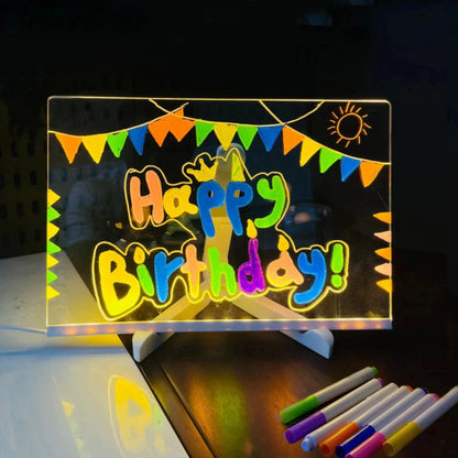 Placa LED colorida com mensagem 'Happy Birthday', bandeirolas e canetas infantis para festa.